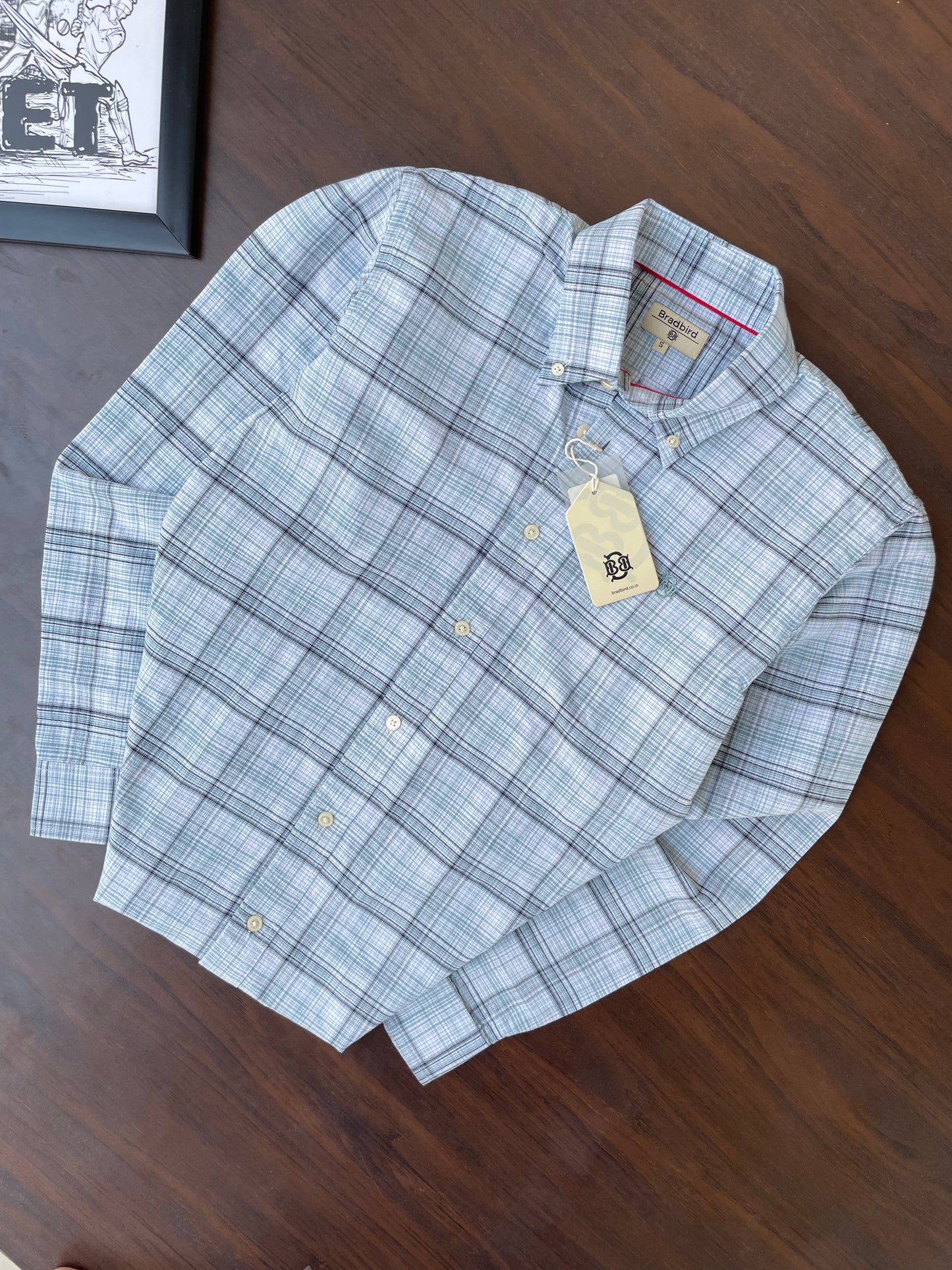 Folded mint-blue oxford check button-up shirt with collar and hanging tag