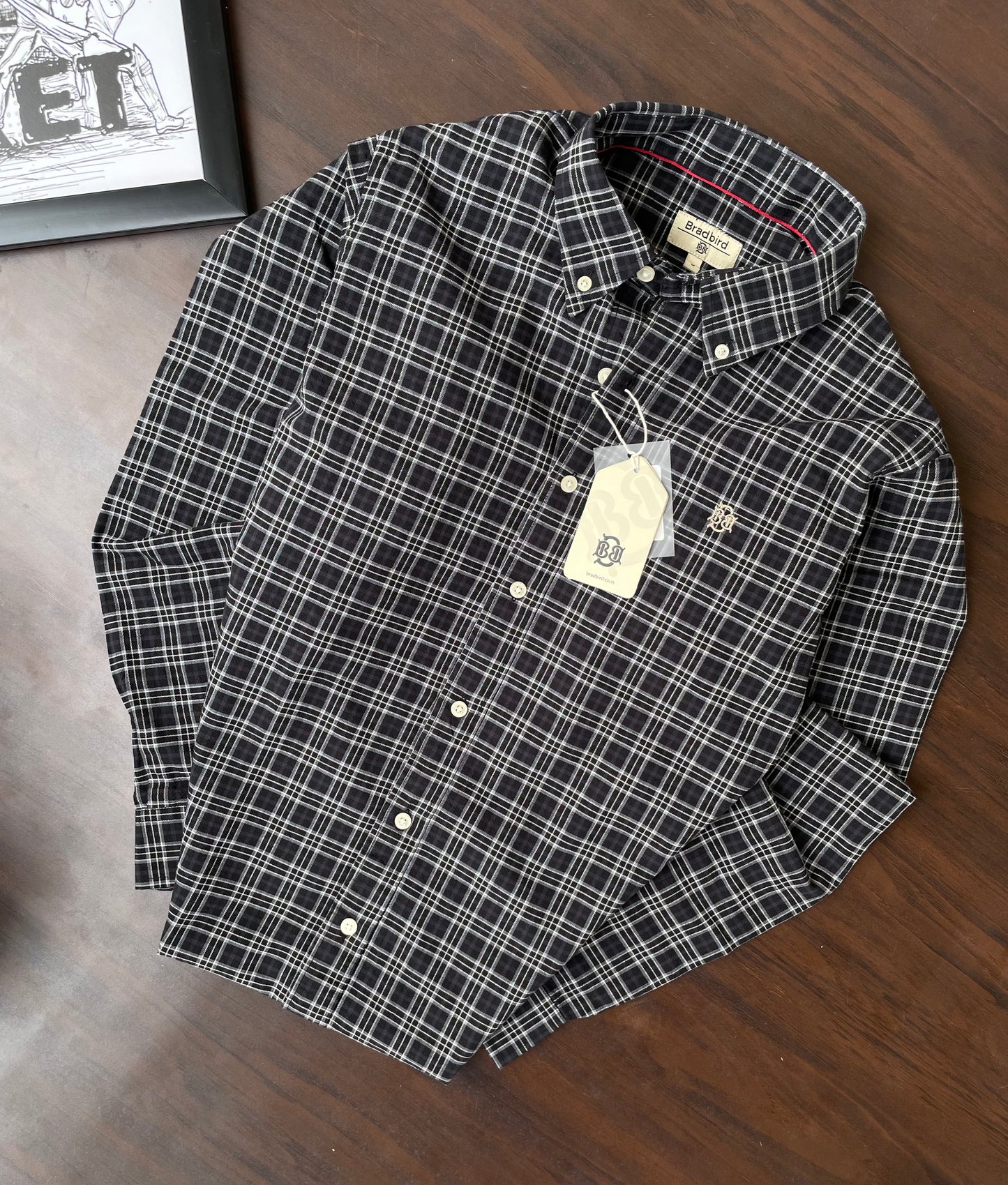 Folded dark checkered button-up shirt with white plaid pattern and collar tags