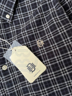Dark and white check shirt fabric with small gold crest logo on chest
