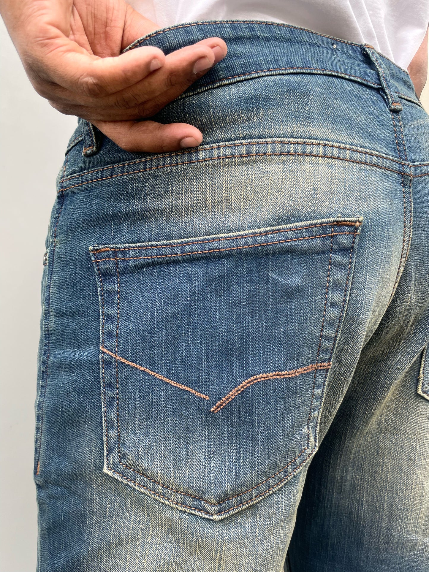 Back pocket and waistband close-up on medium blue denim straight jeans