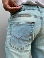 Close-up of light wash denim back pocket with contrast stitching and seam details