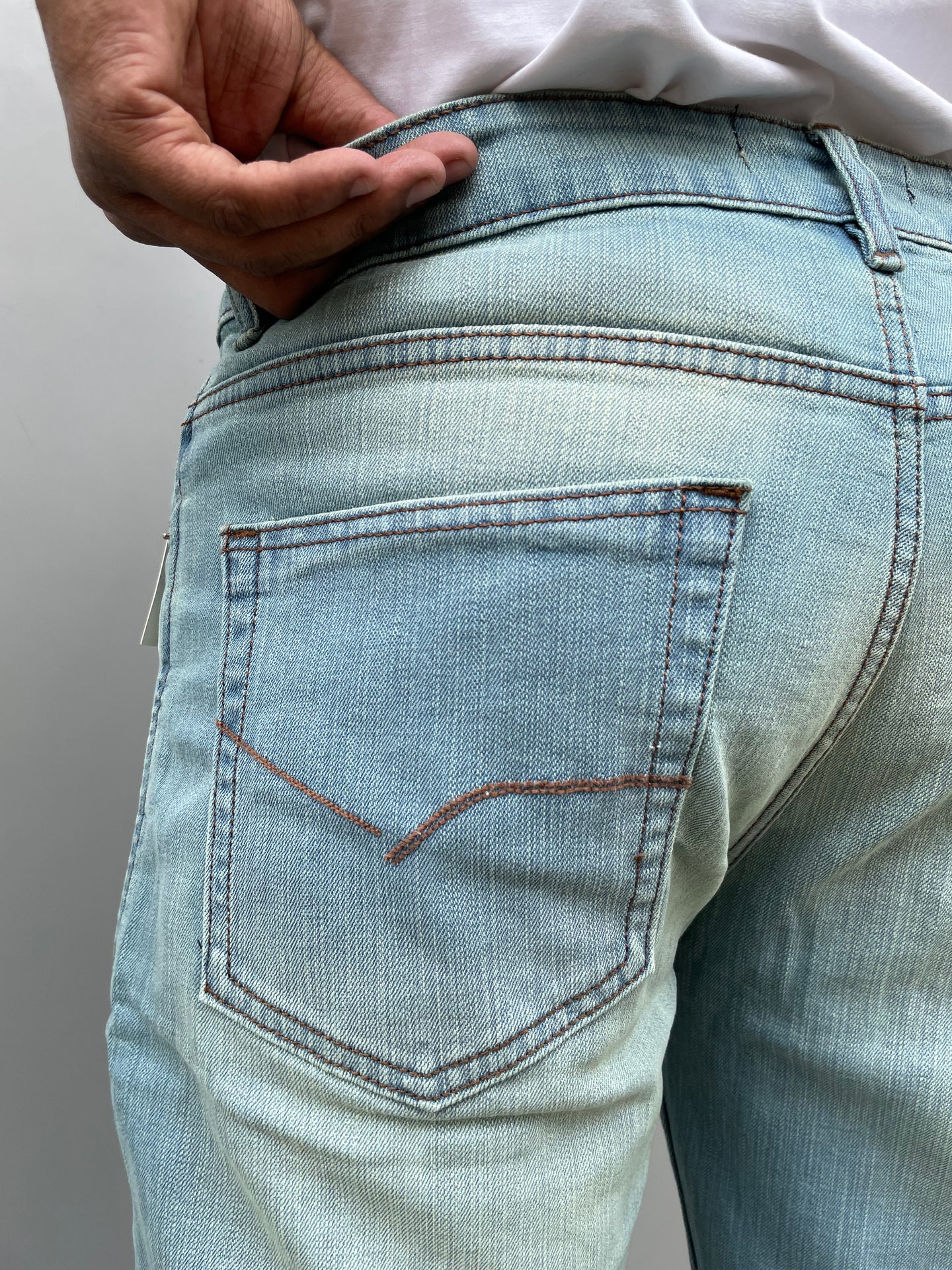Close-up of light wash denim back pocket with contrast stitching and seam details
