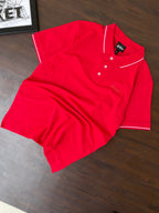 Folded red polo shirt with white button placket and collar tipping detail