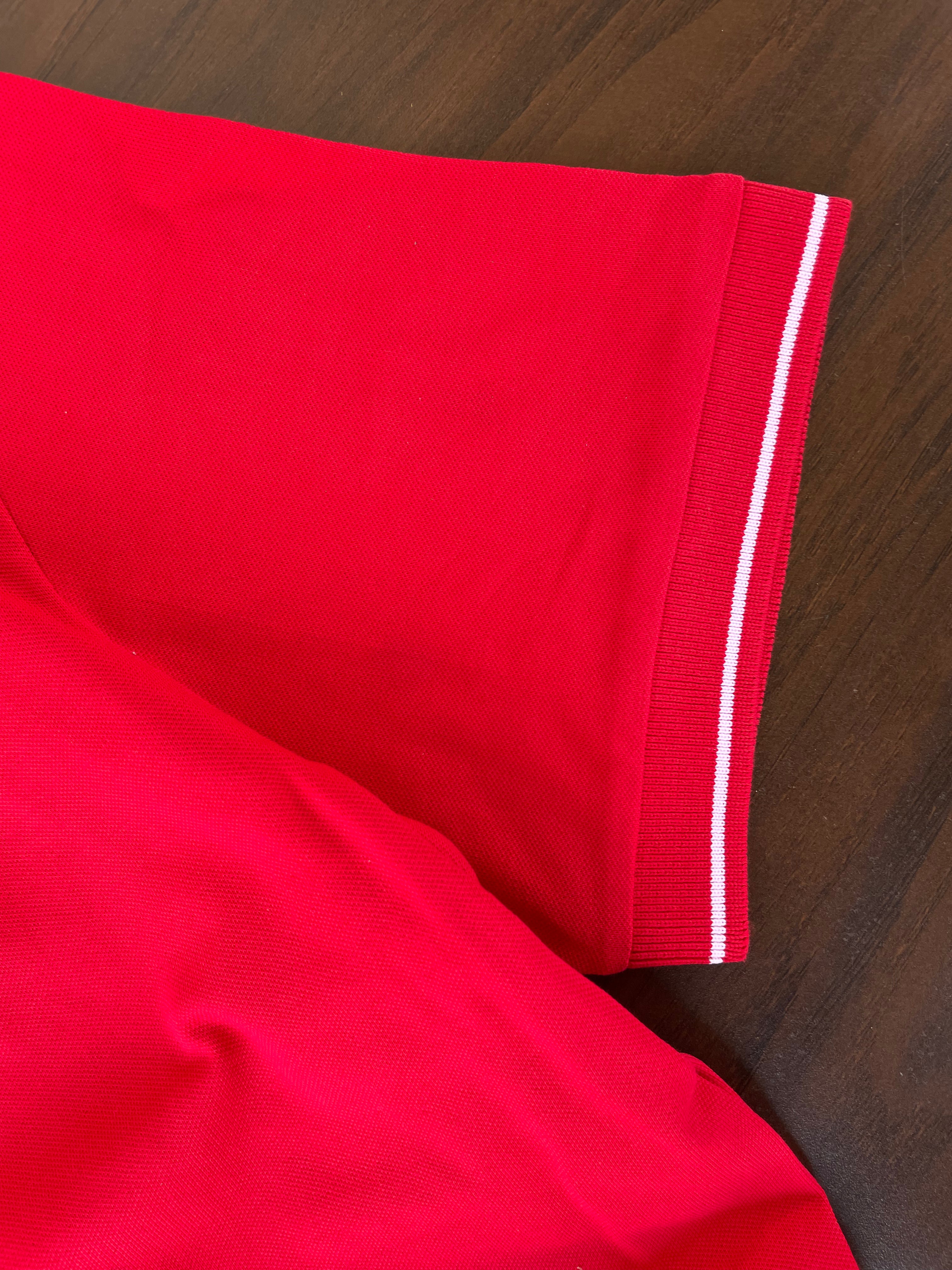 Red polo sleeve and hem with white striped tipping detail along the cuff