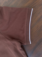 Coffee brown polo shirt sleeve cuff with white contrast stripe and curved hem.