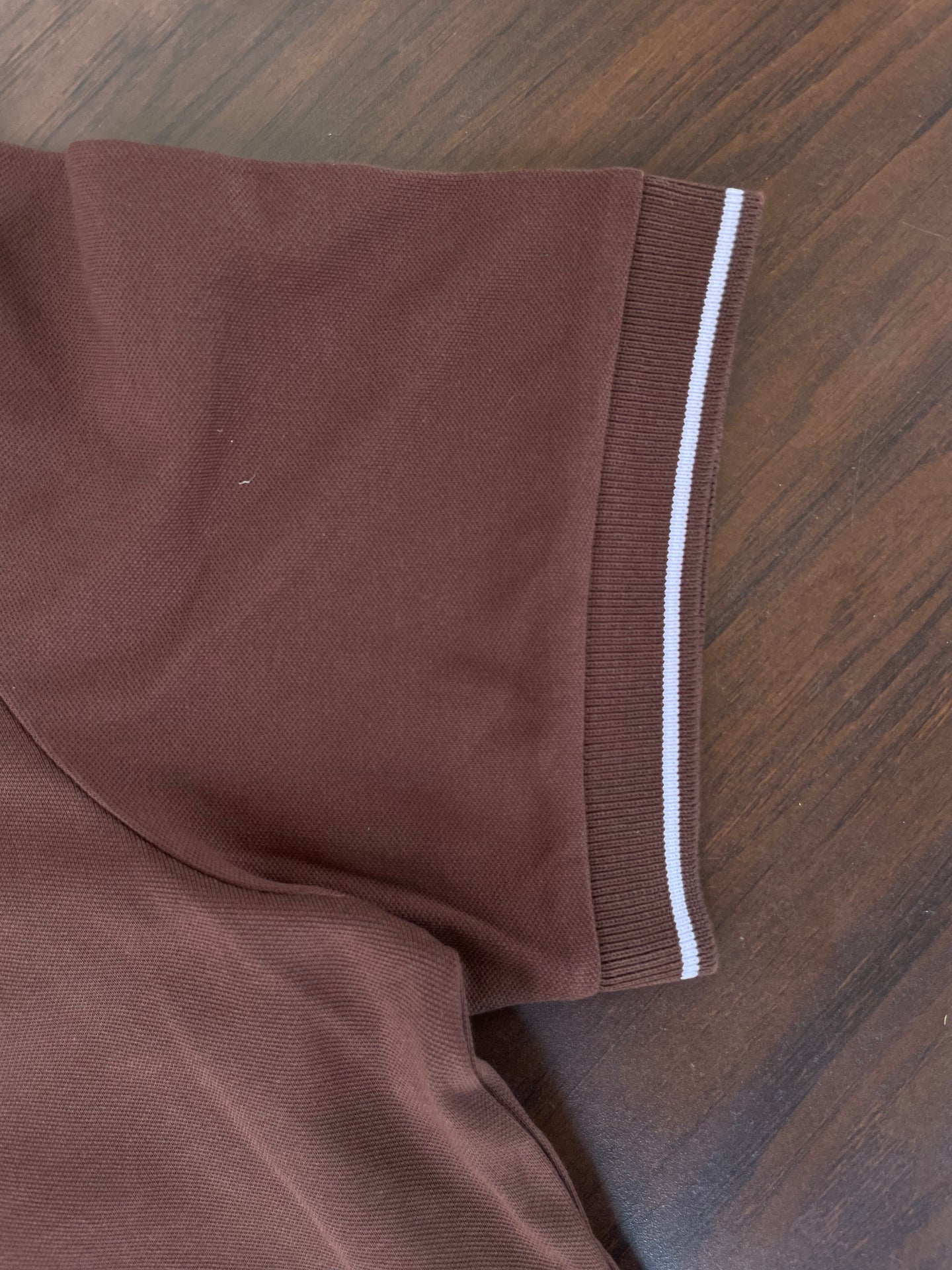 Brown polo sleeve cuff with white contrast stripe and smooth knit fabric
