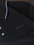 Black polo shirt close-up: white collar edge, button placket, embroidered logo