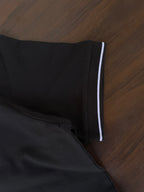 Black polo shirt sleeve trim with white stripe band at cuff