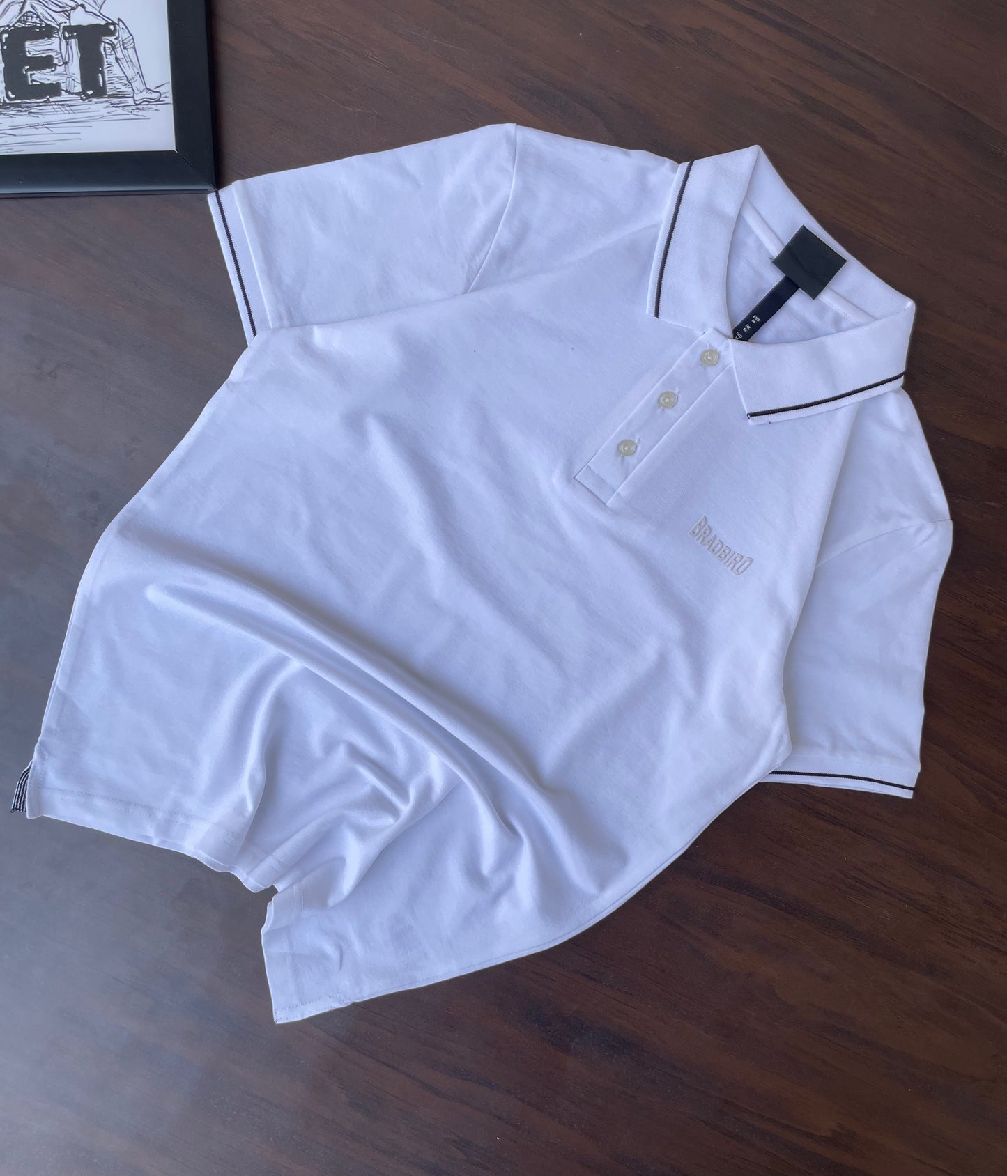 Folded white polo shirt with black-trim collar and placket, short sleeves