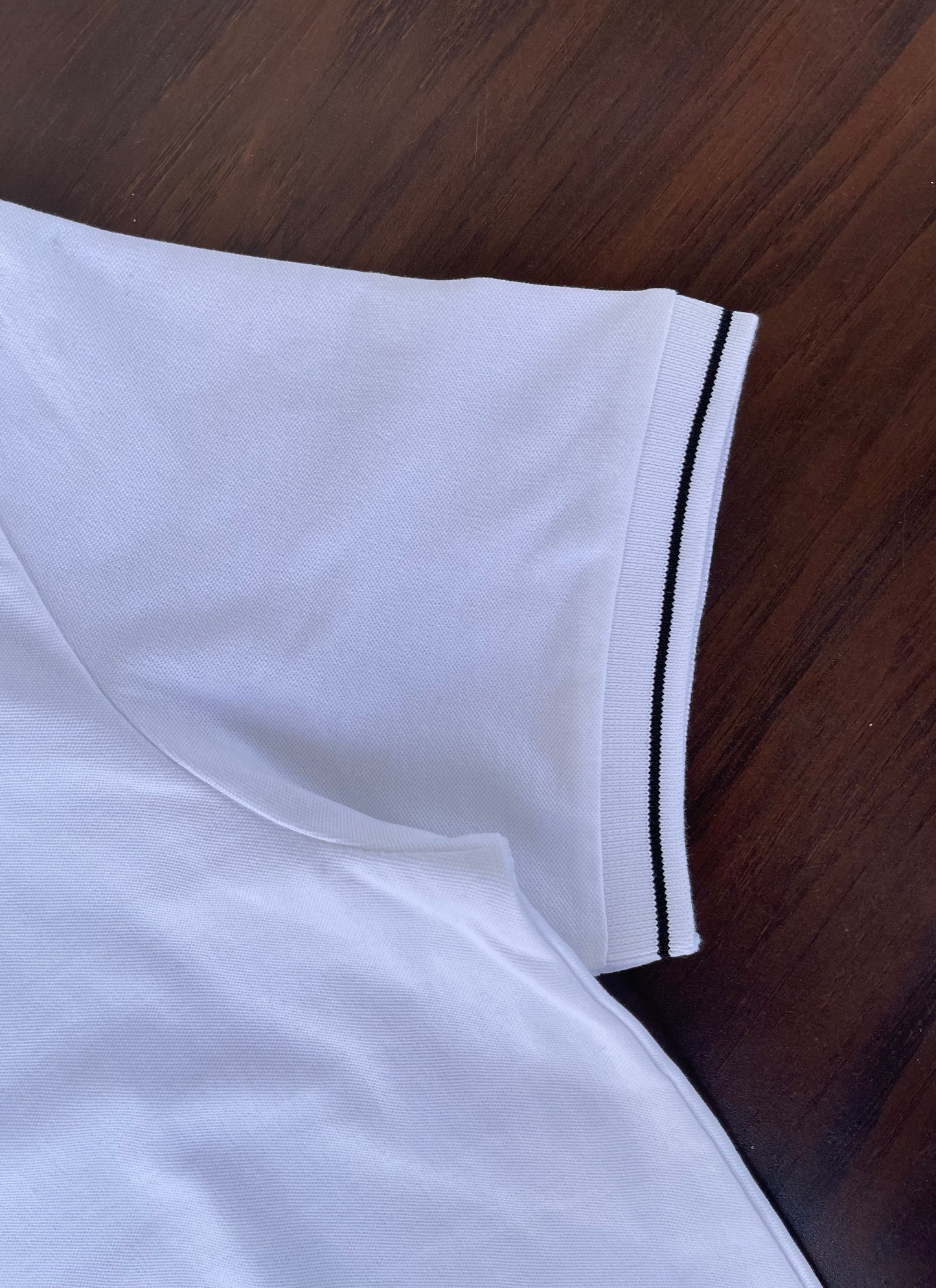 White polo sleeve hem with black stripe trim