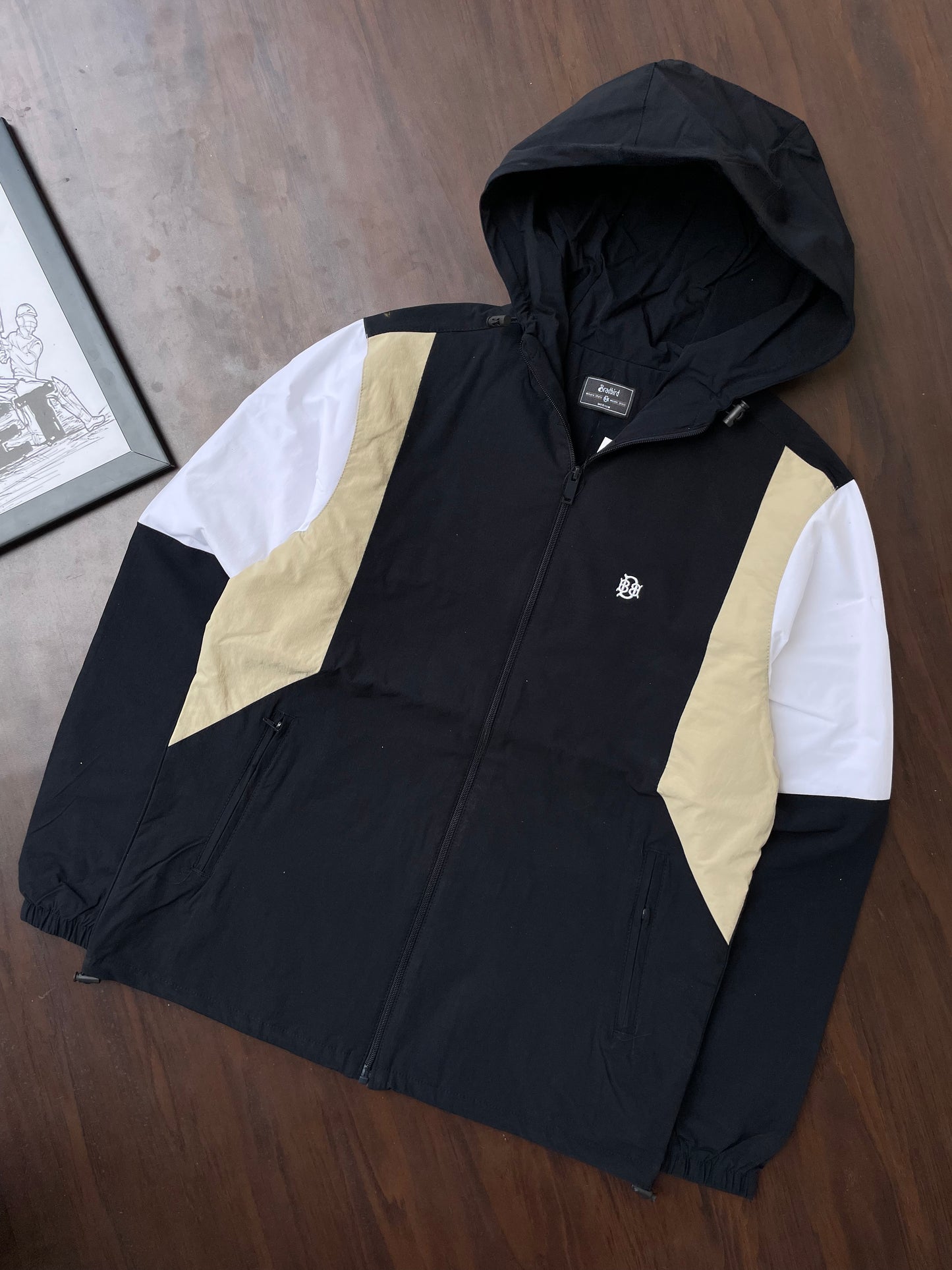 Black hooded windbreaker with sand and white panels on sleeves, zip front