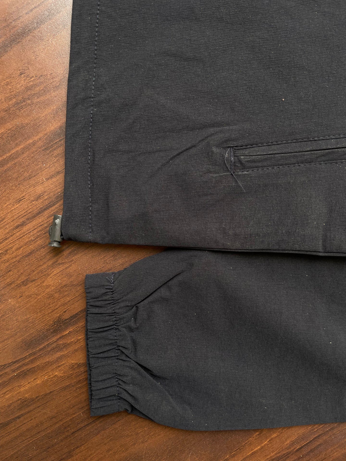 Black windbreaker hem and sleeve cuff with elastic edge and stitched seam