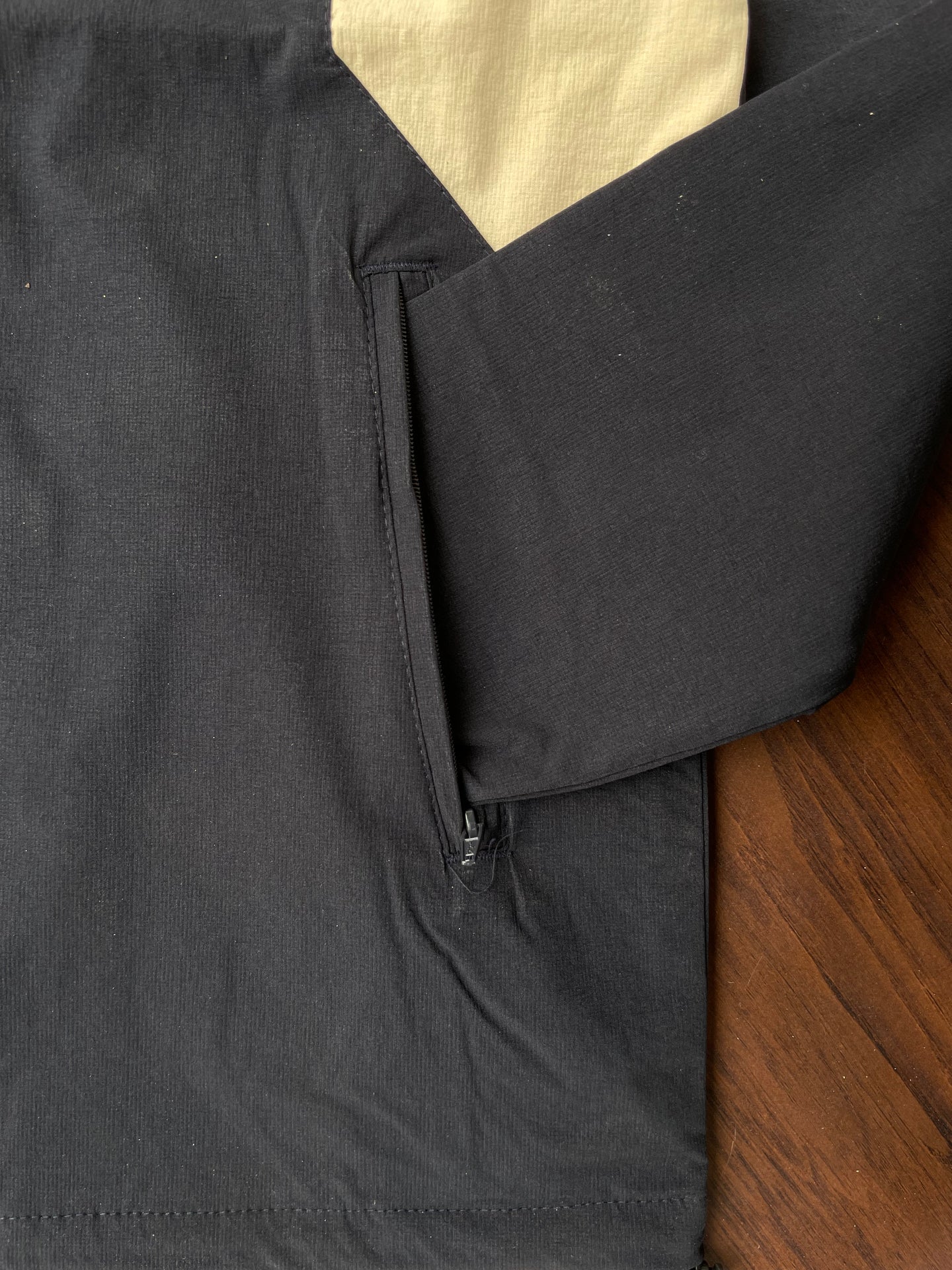 Black windbreaker side zipper pocket area with sand and white panel insert