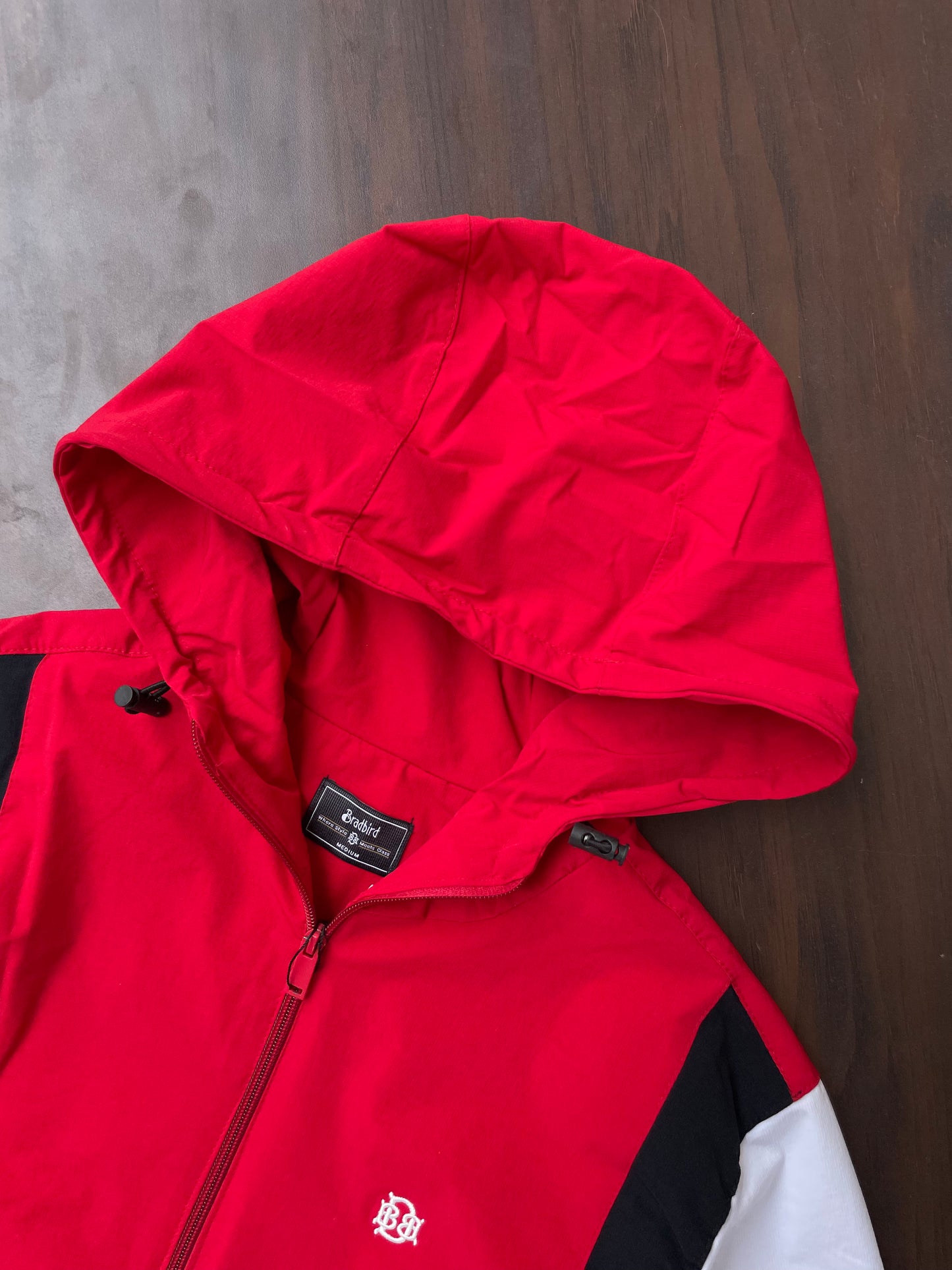 Scarlet red hooded windbreaker with black-and-white accents, hood and front view close