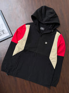 Black hooded windbreaker jacket with red sleeves and sand center panels, full zipper
