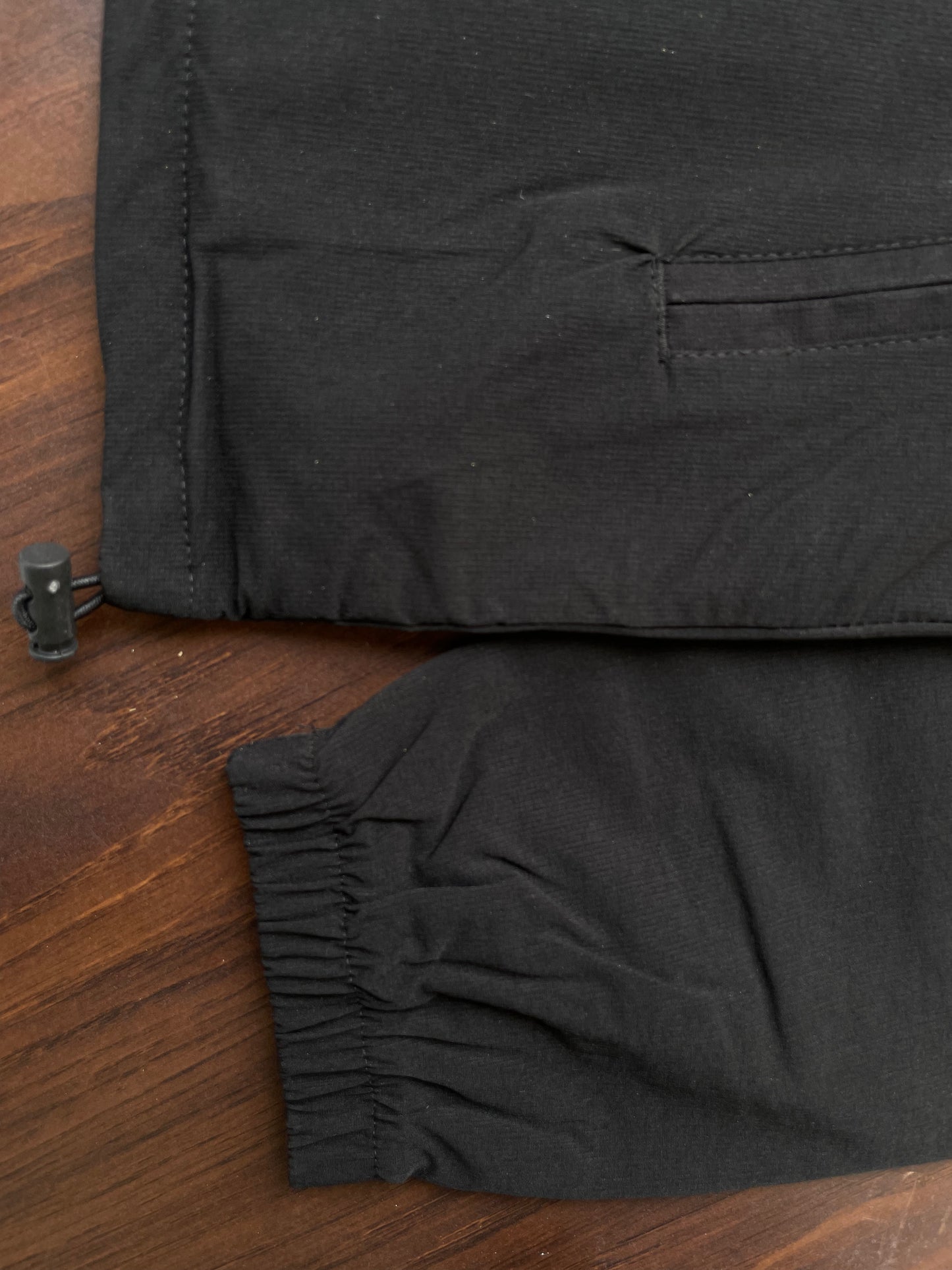 Black windbreaker sleeve cuff with elastic hem and small drawstring stopper
