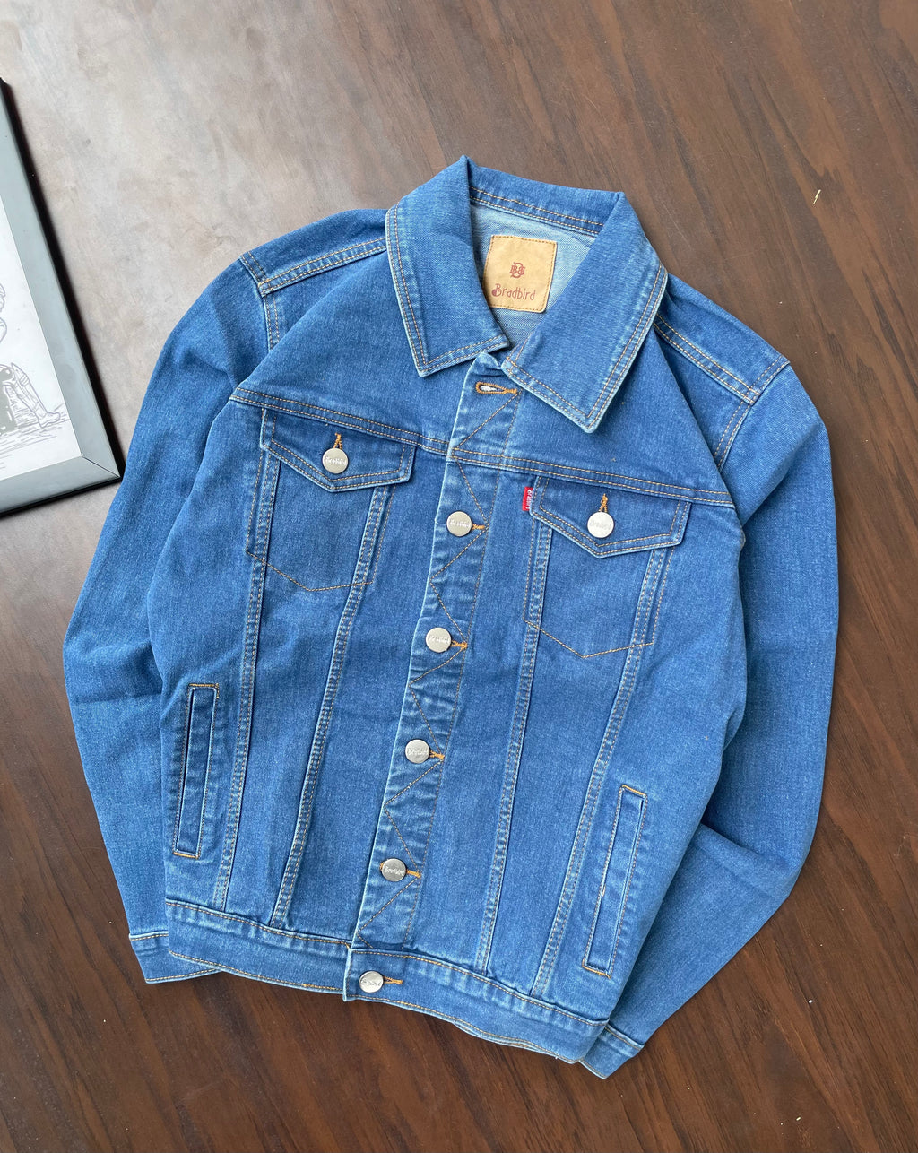 Blue medium-wash denim trucker jacket with pointed collar and chest pockets