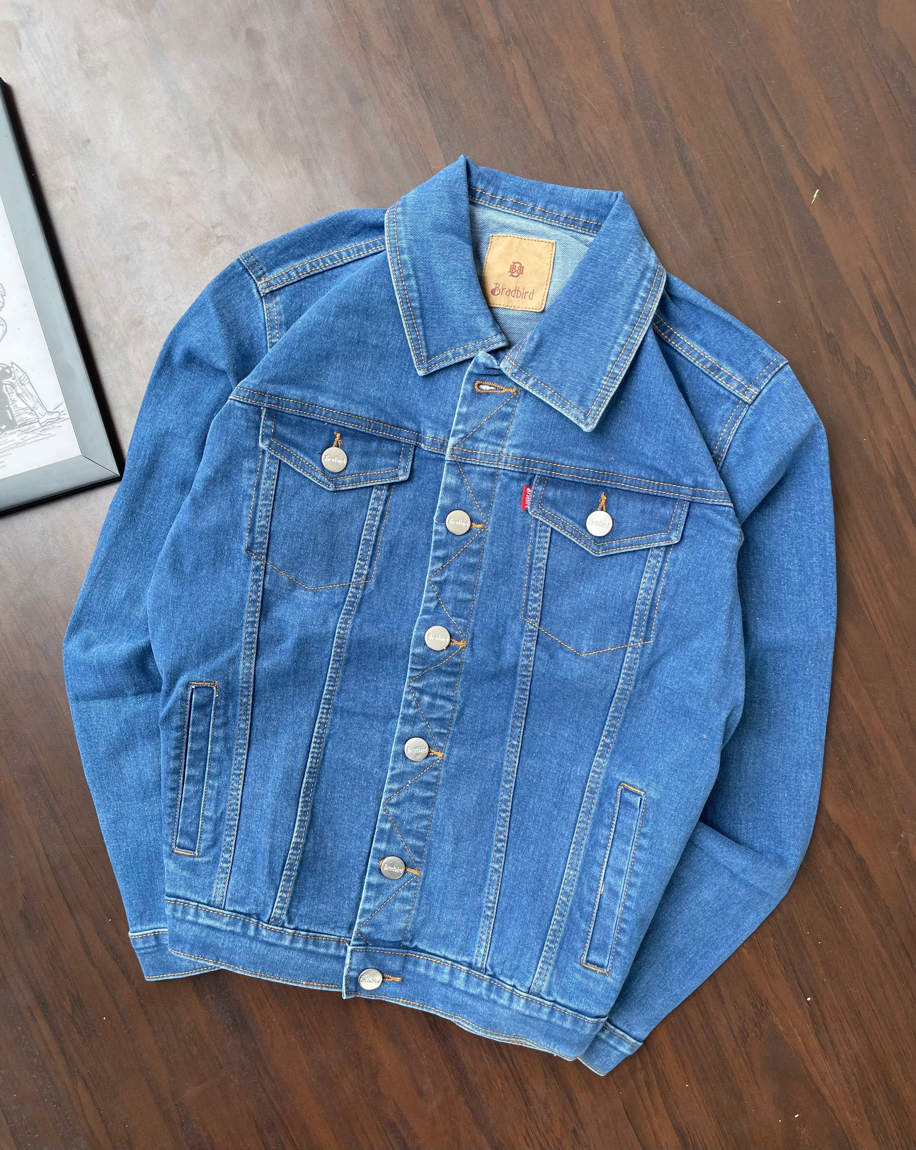 Blue medium-wash denim trucker jacket with pointed collar and chest pockets