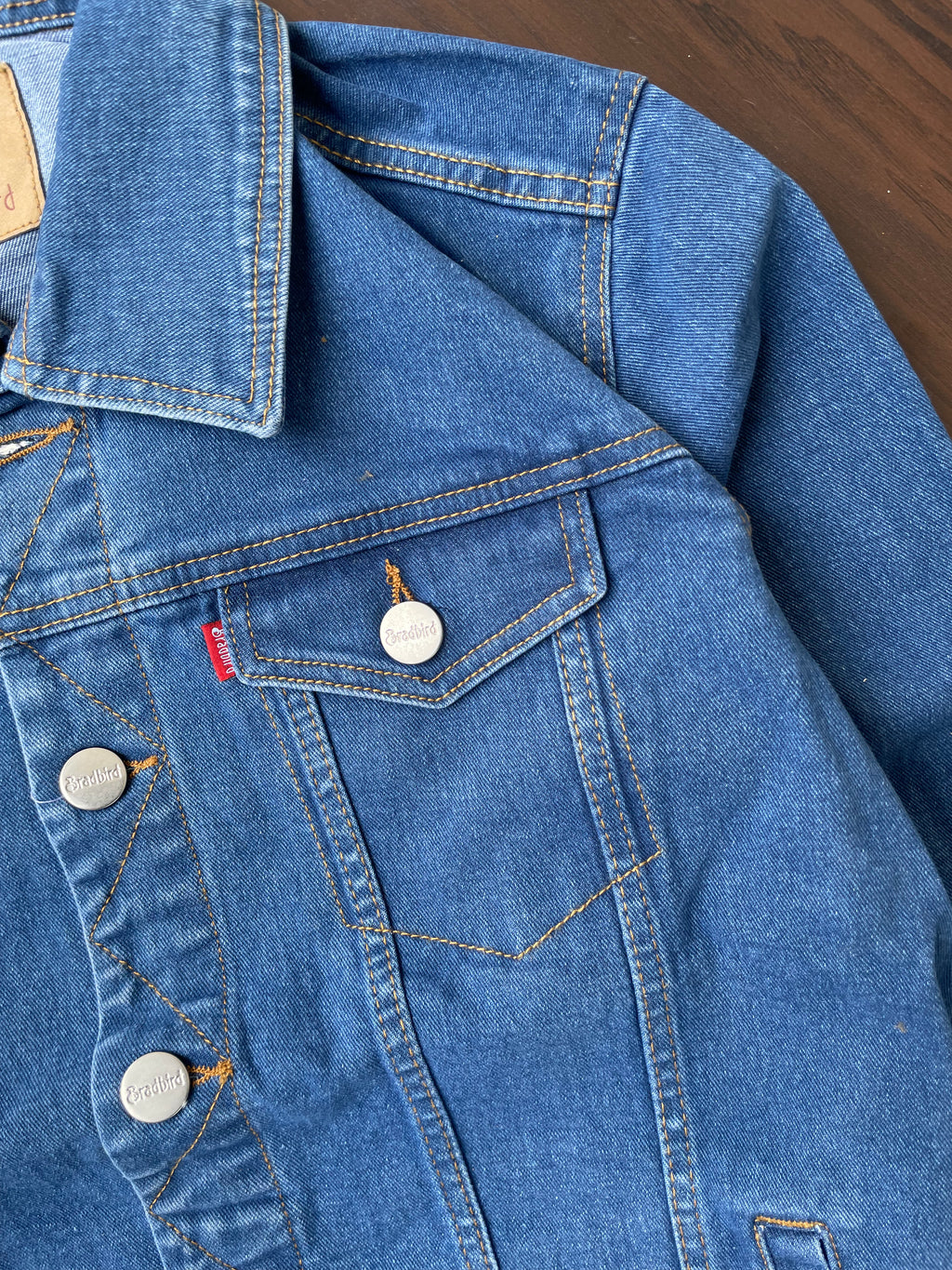 Close-up of medium-wash denim jacket with flap chest pocket and metal buttons