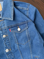 Close-up of medium-wash denim jacket with flap chest pocket and metal buttons