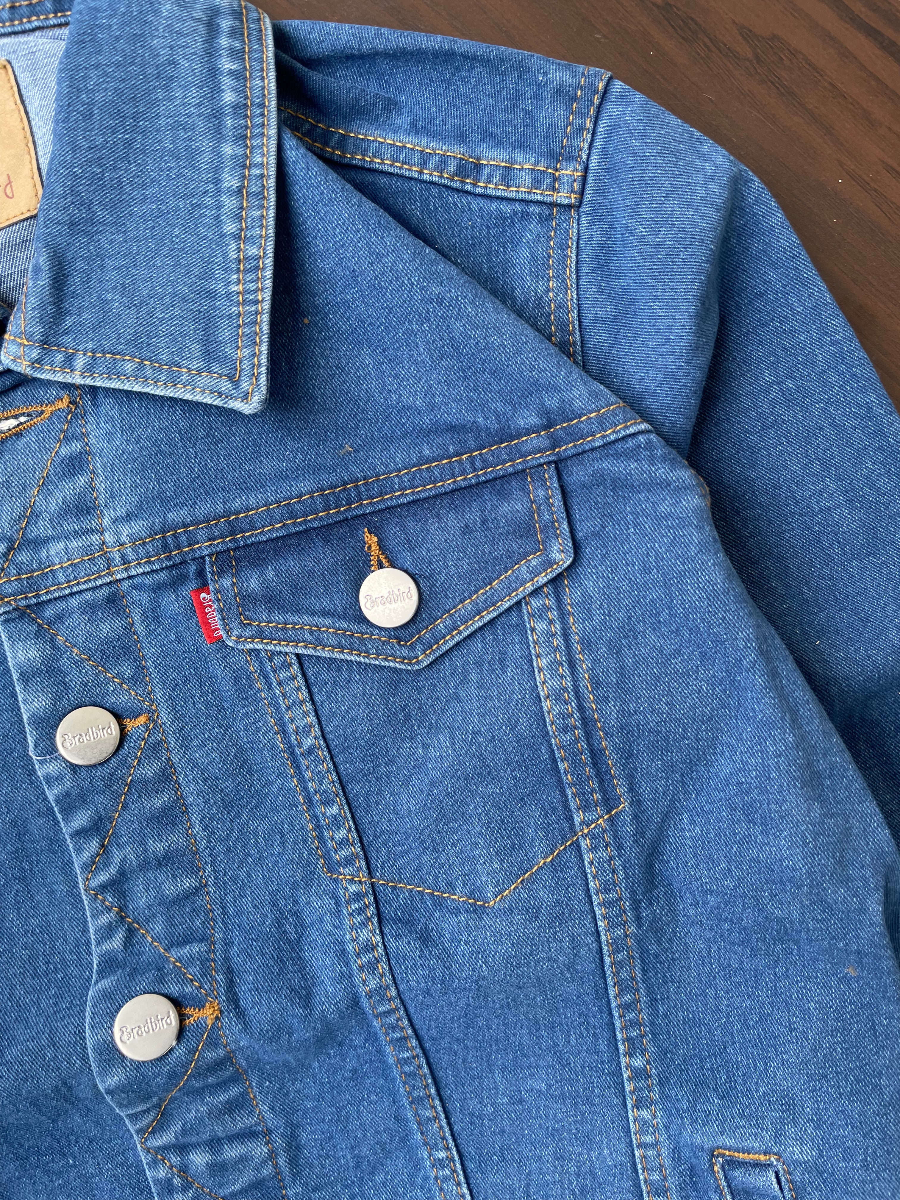 Close-up of medium-wash denim jacket with flap chest pocket and metal buttons