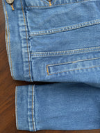Bottom hem and sleeves of medium-wash denim jacket with topstitching