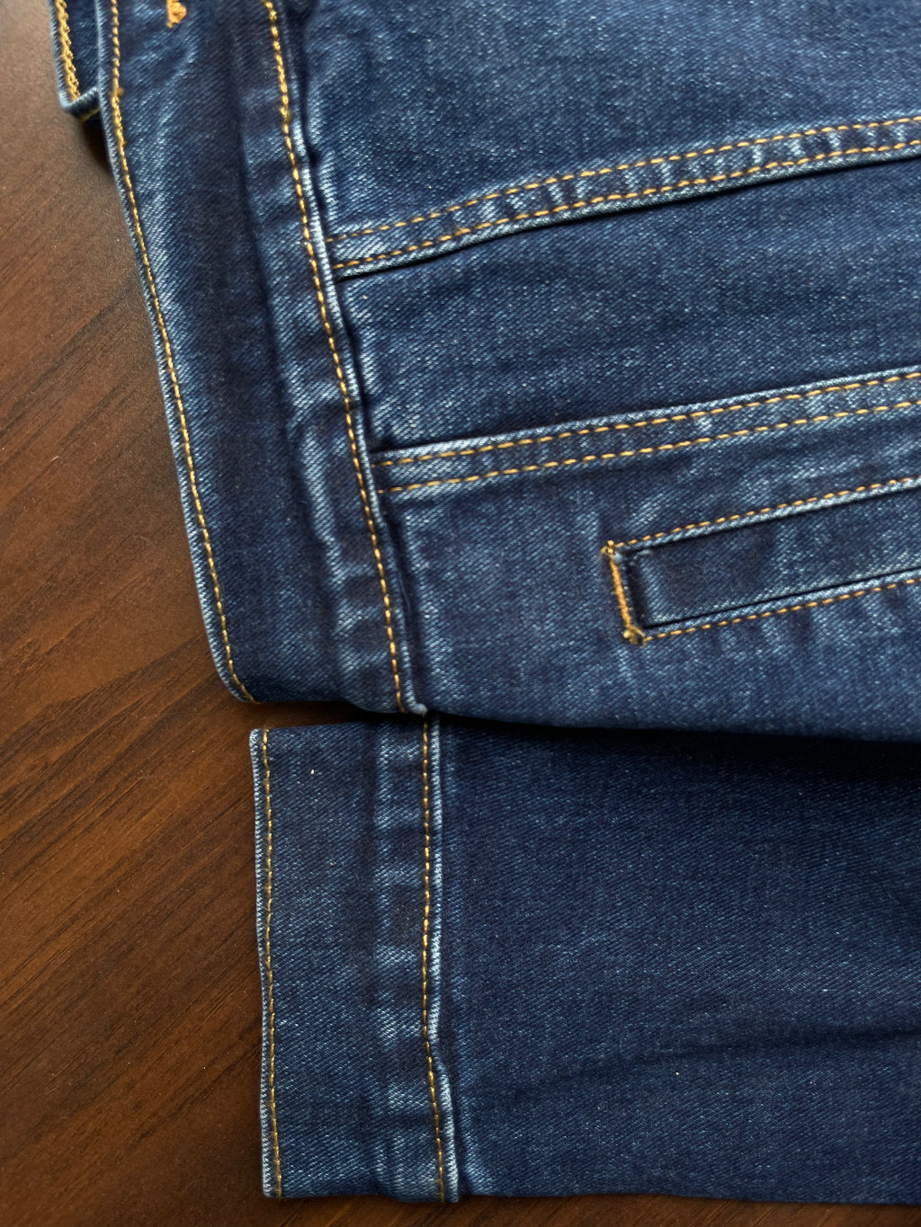 Denim jacket sleeve cuff and hem close-up with contrast yellow topstitching