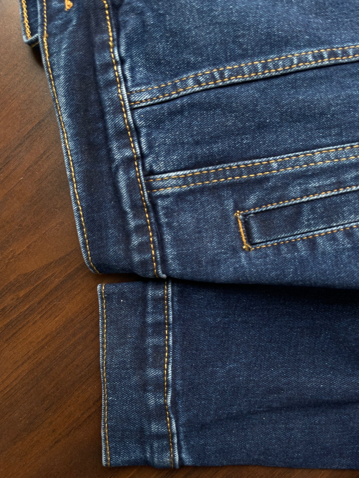 Denim jacket sleeve cuff and hem close-up with contrast yellow topstitching
