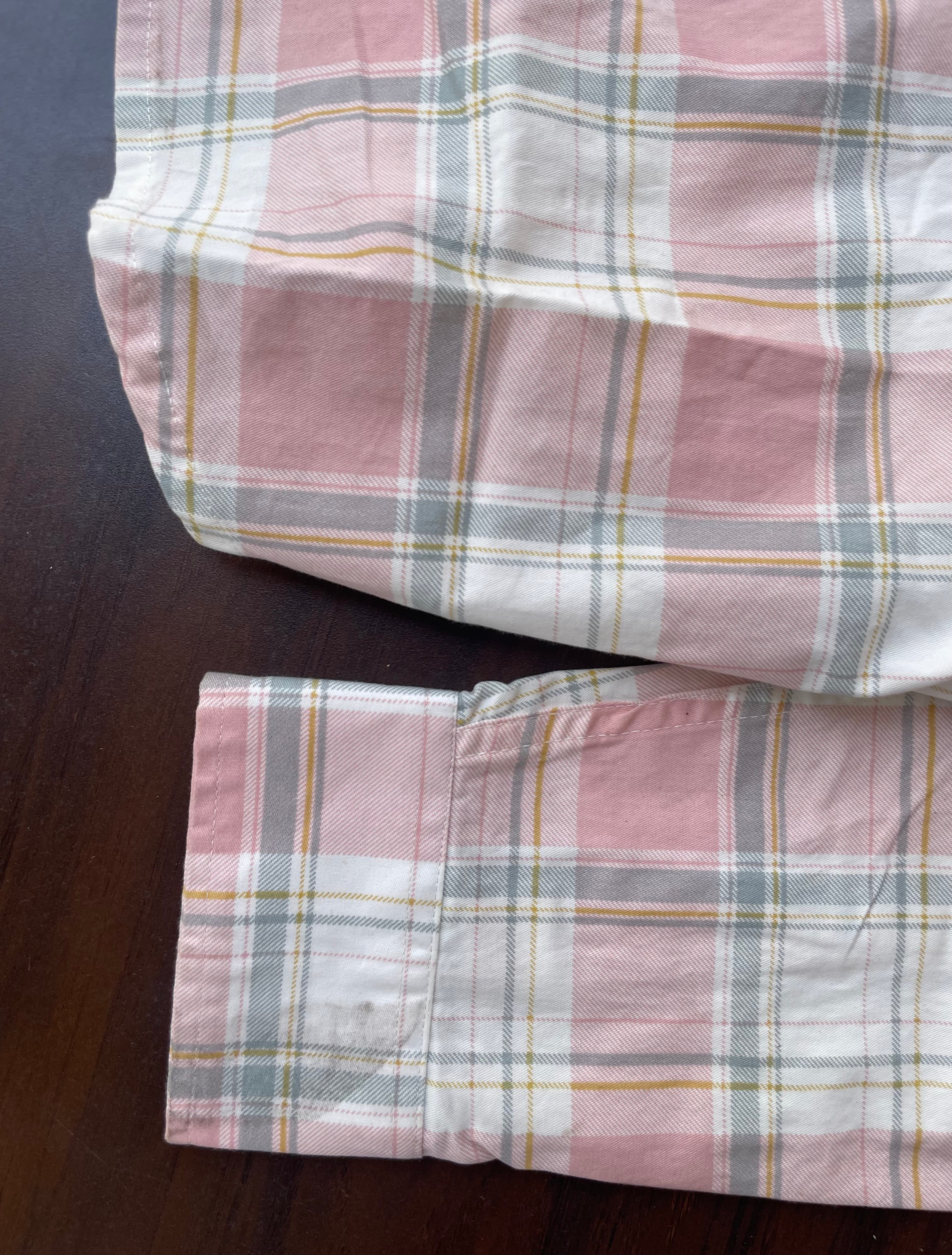 Dusty pink plaid western shirt cuff area with buttoned sleeve opening