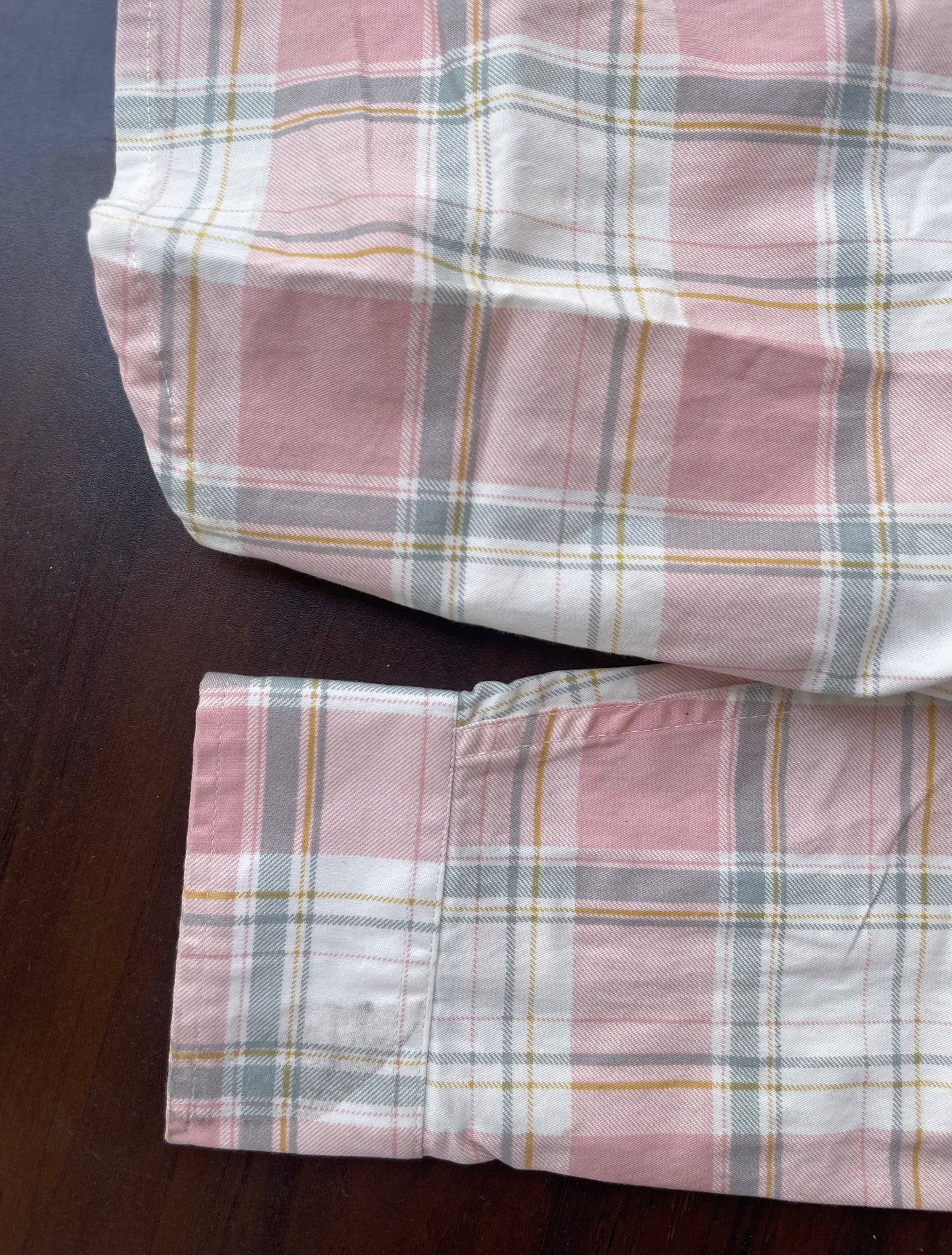 Dusty pink plaid western shirt cuff area with buttoned sleeve opening