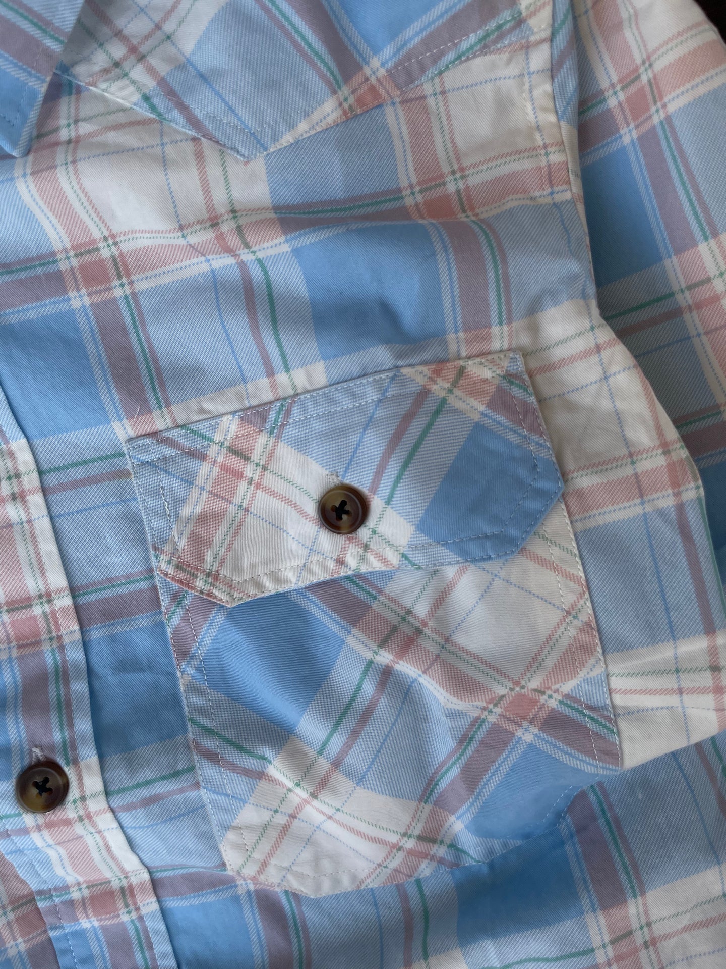 Front pocket and snap buttons on sky blue plaid western shirt