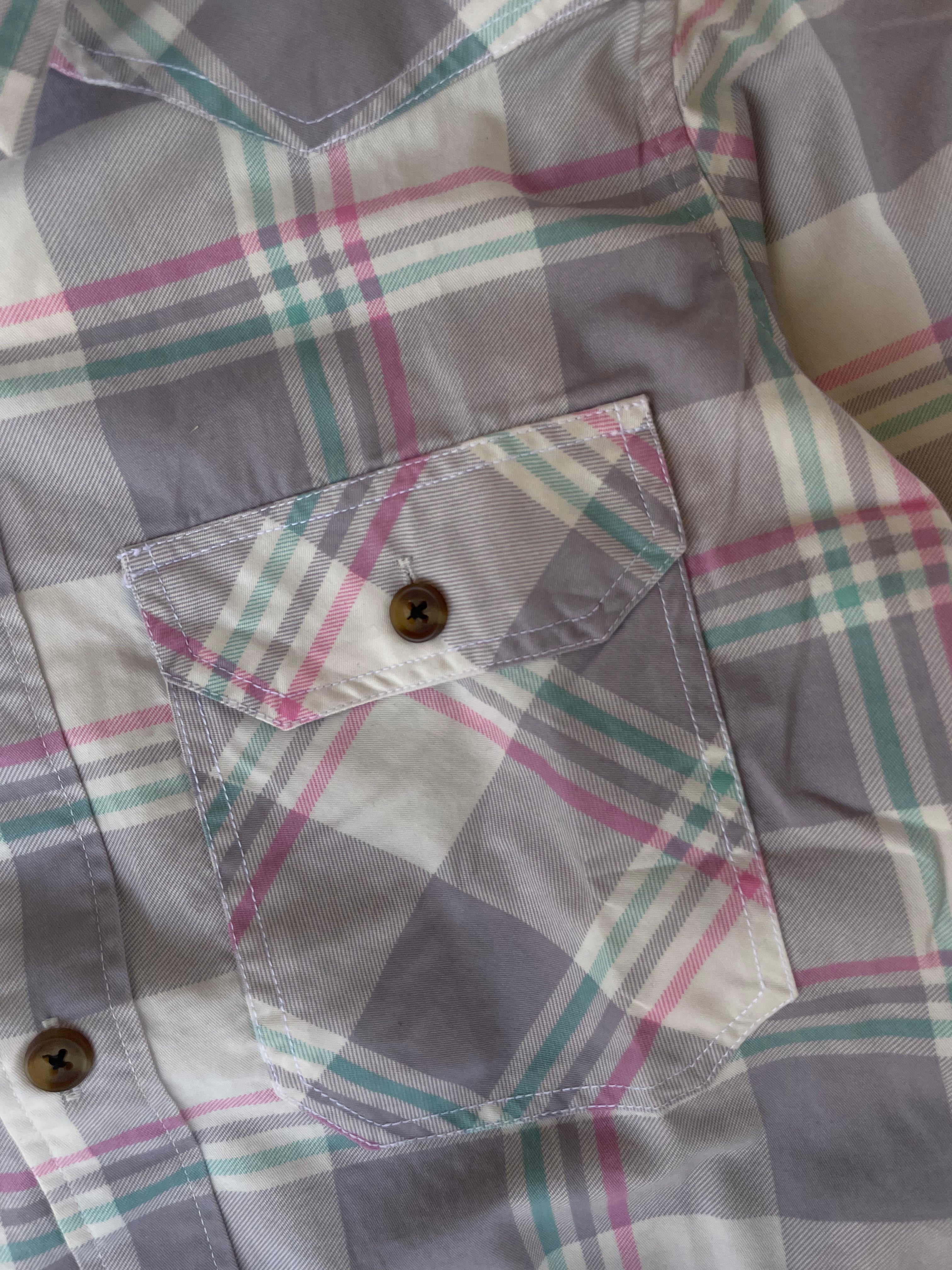Close-up of plaid yoke and flap chest pocket with button on western shirt
