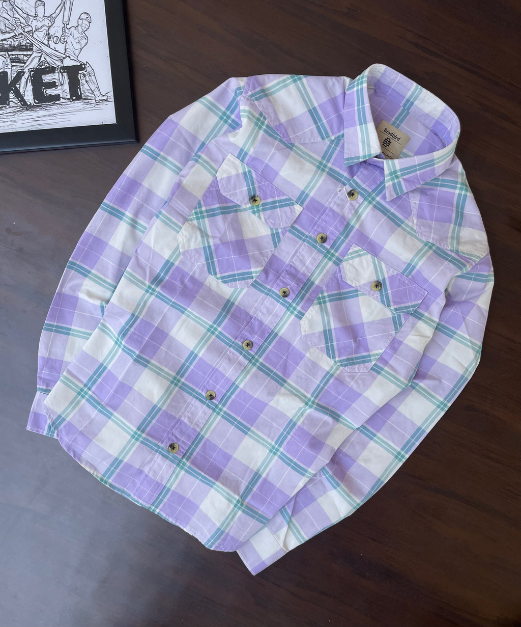 Purple and teal plaid western shirt, folded flat, with snap button front and chest pockets