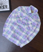 Purple and teal plaid western shirt, folded flat, with snap button front and chest pockets