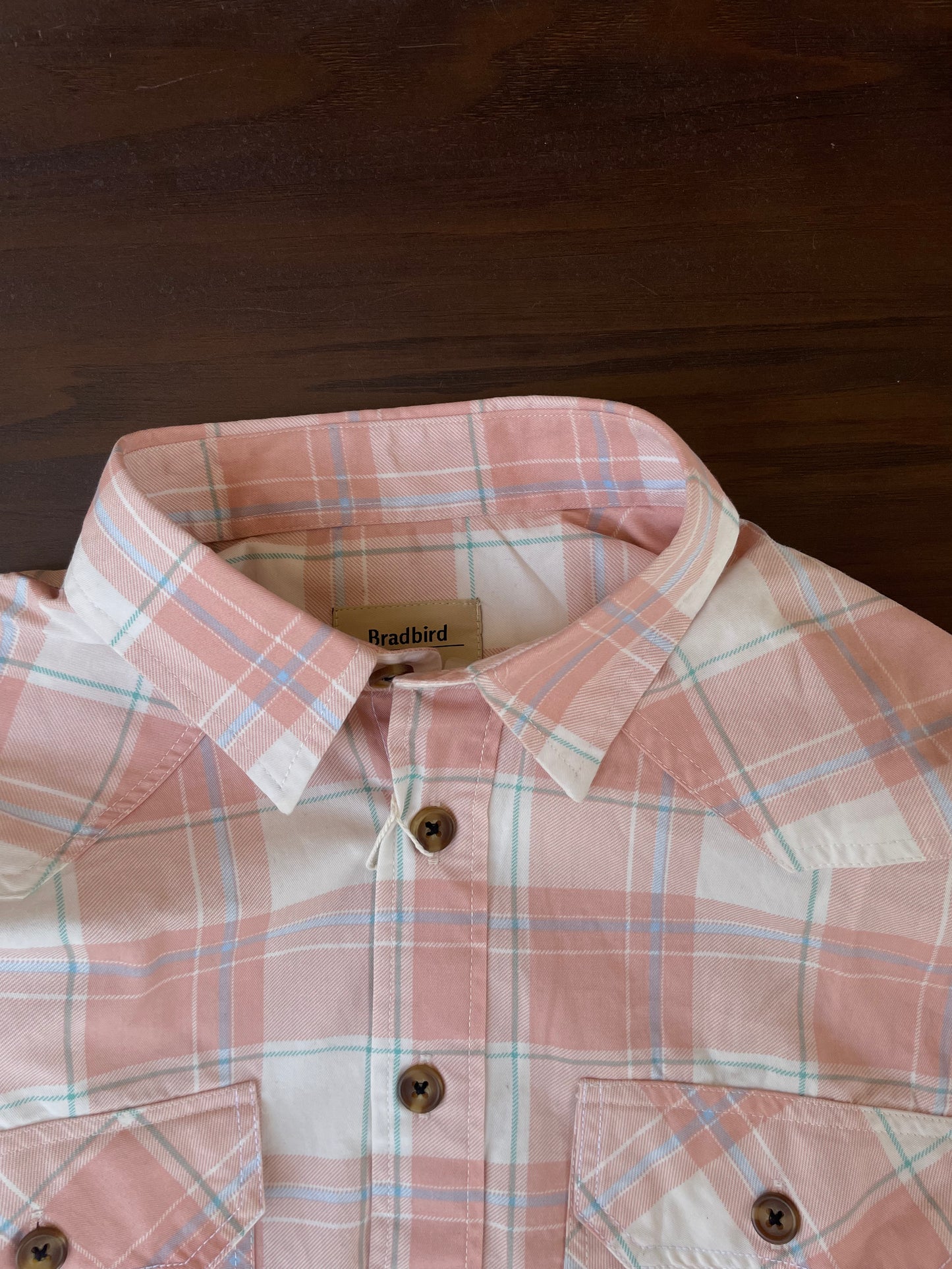 Peach-and-white plaid western shirt close-up: button collar and two chest pockets