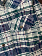 Close-up of green and navy plaid cotton shirt chest pocket with button detail