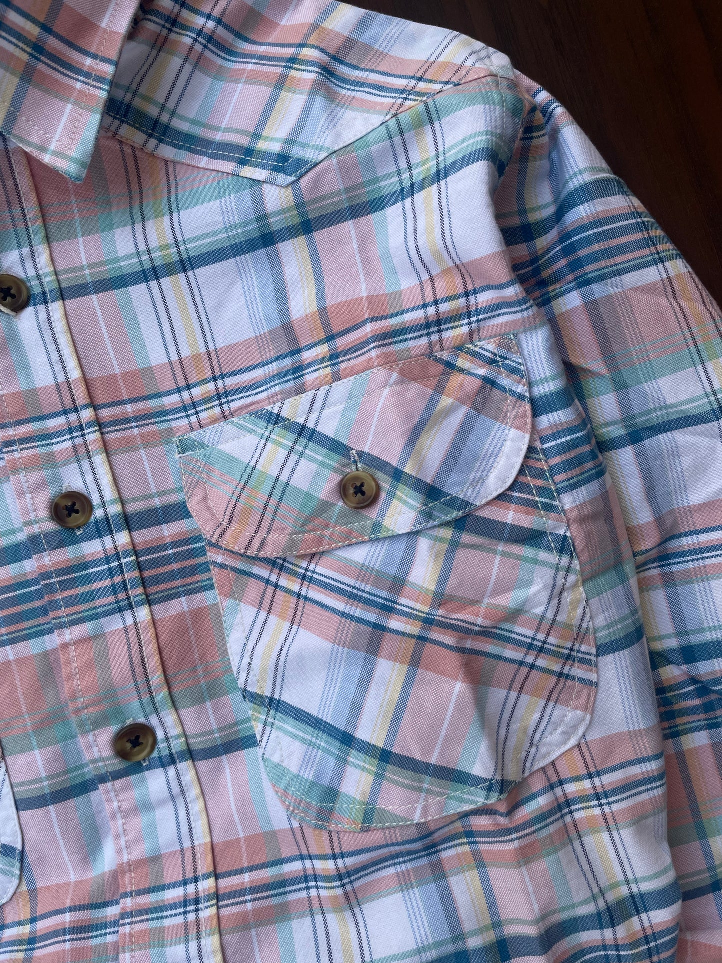 Close-up pastel plaid dual flap chest pockets with brown button details