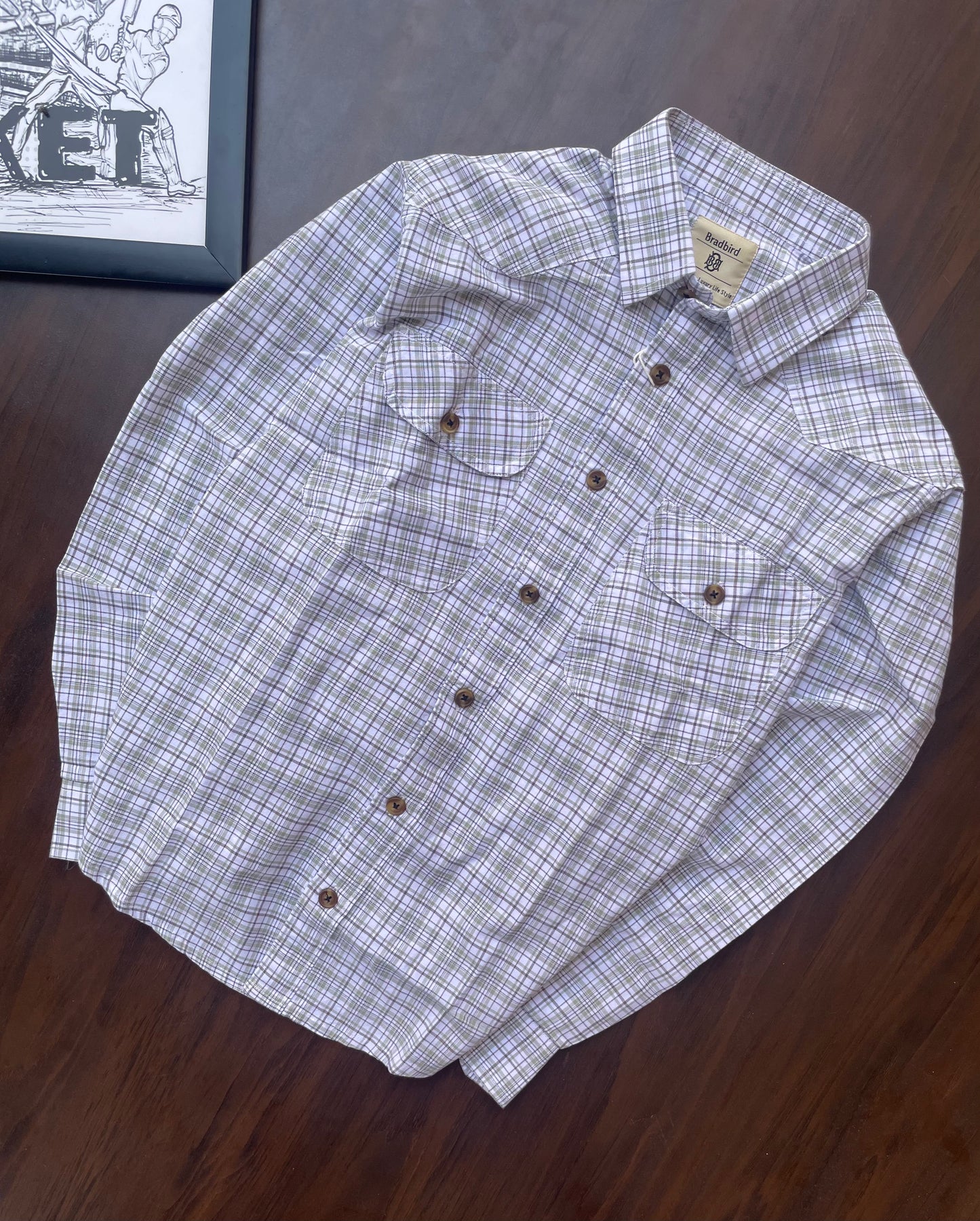 Folded men’s plaid button-up shirt, white base with grey and green grid checks