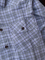 Close-up of chest pocket and buttons on plaid shirt, white with blue-grey checks