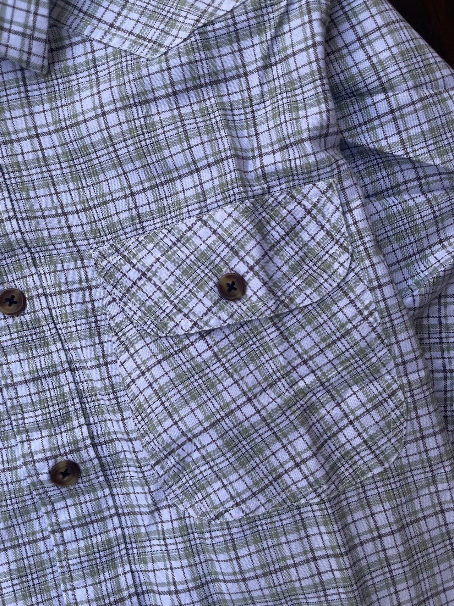 Close-up of chest pocket and buttons on plaid shirt, white with blue-grey checks