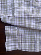 Sleeve and hem detail of plaid shirt, white with blue-grey and green grid checks