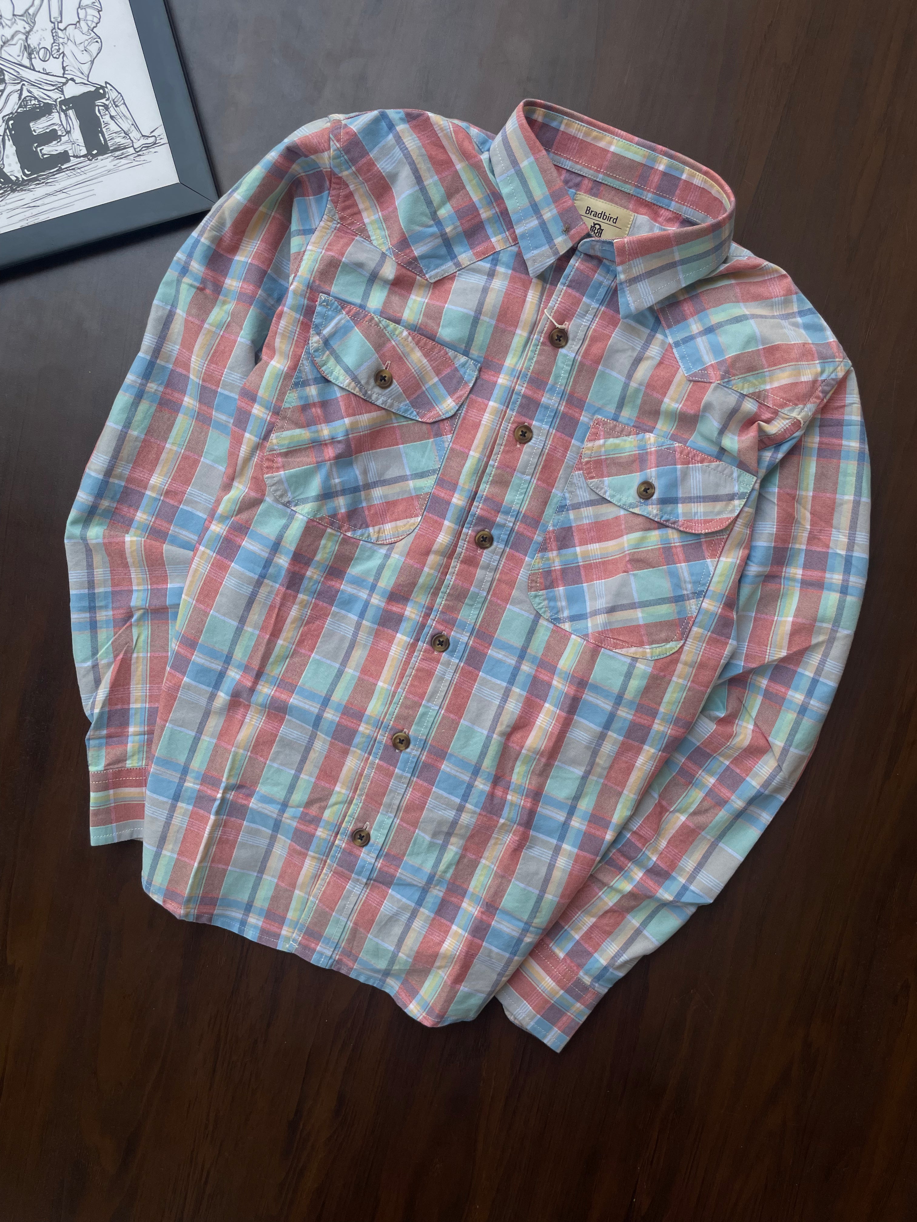 Folded casual shirt with bold red, blue, and green plaid; button front and chest pockets