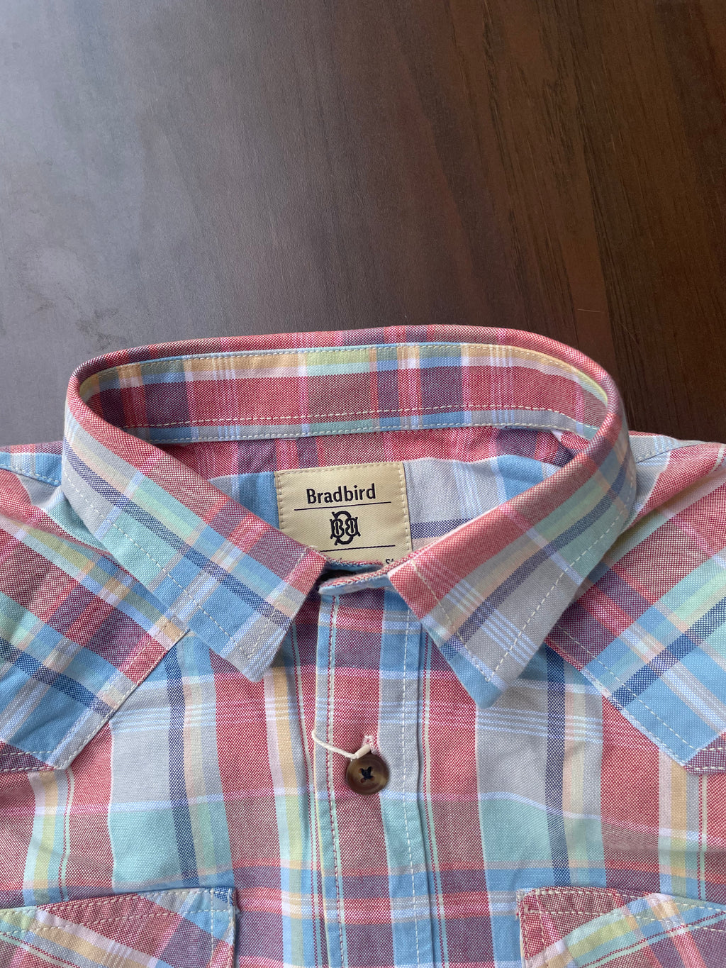 Collar and placket of red, blue, and green plaid casual shirt with brown button