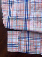 Pink and blue plaid cotton shirt hem and folded sleeve, buttoned panel visible