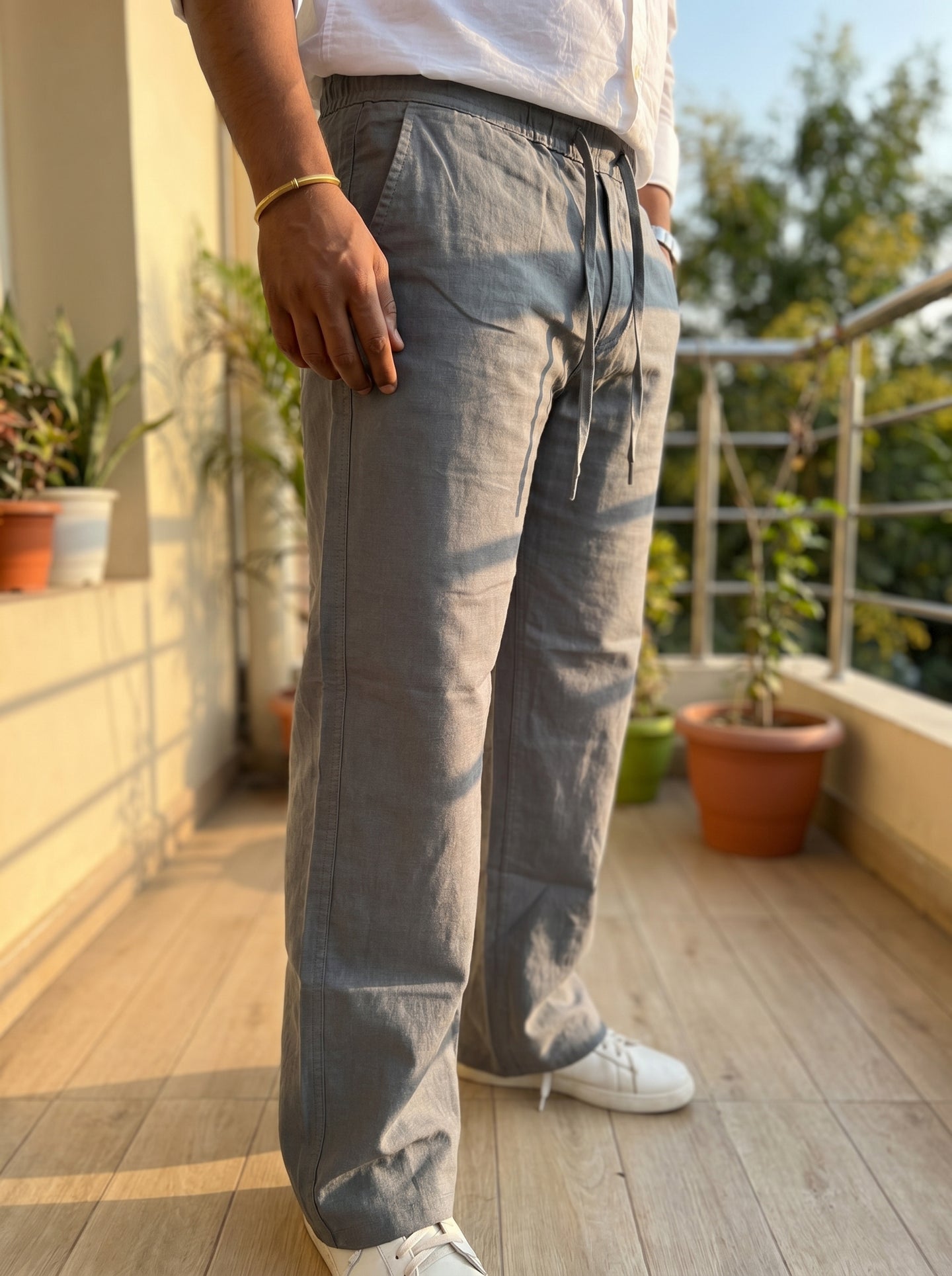 Light grey relaxed drawstring pants with elastic waist and cuffs, outdoor side view