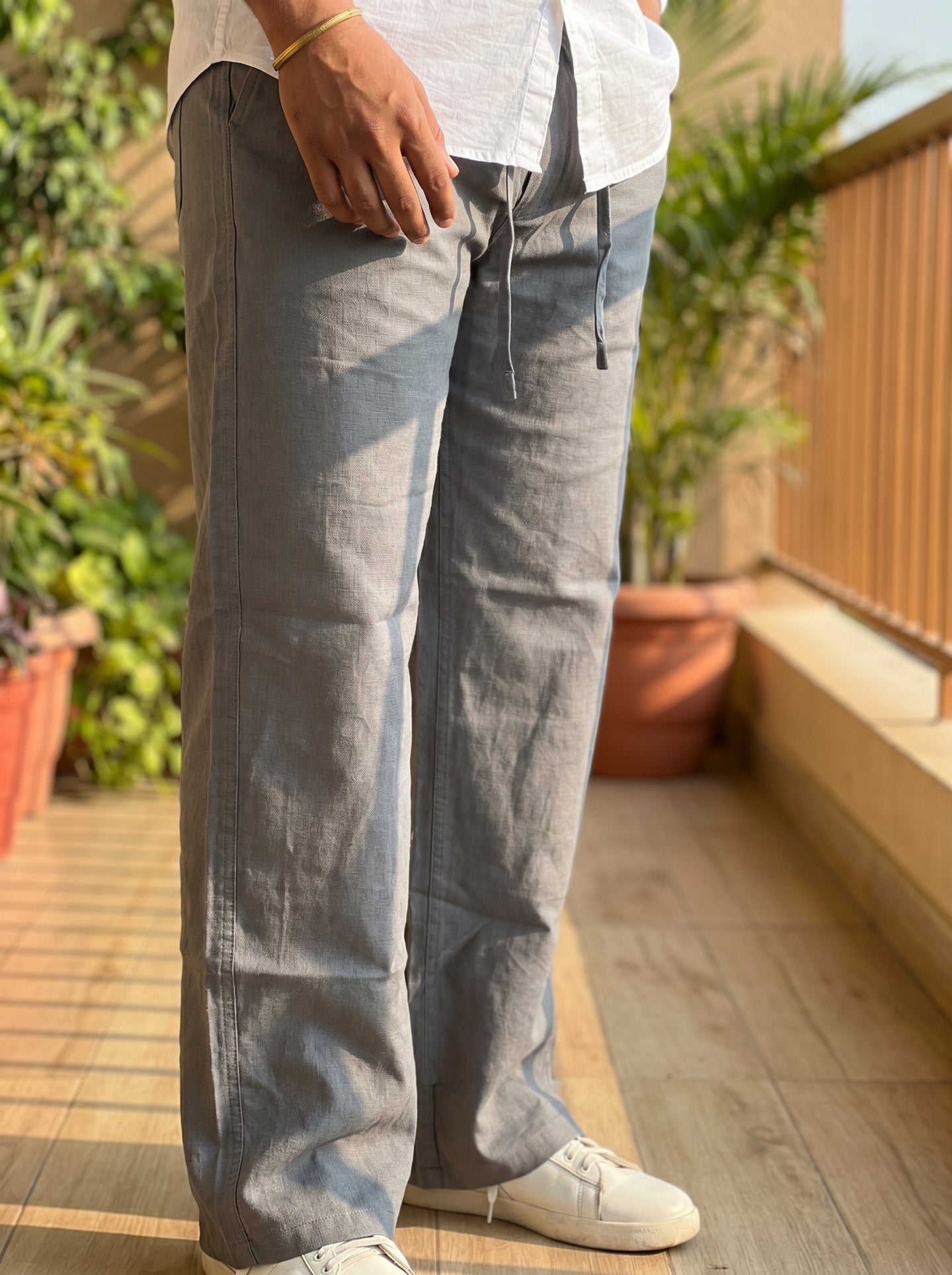 Light grey drawstring pants with pockets, relaxed fit, hand holding waistband