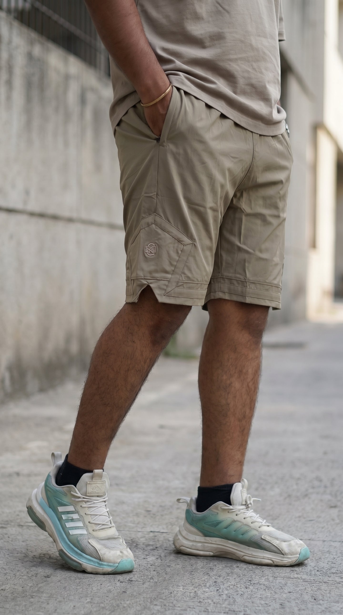 Olive-brown shorts with pentagonal cargo pocket and embroidered logo detail