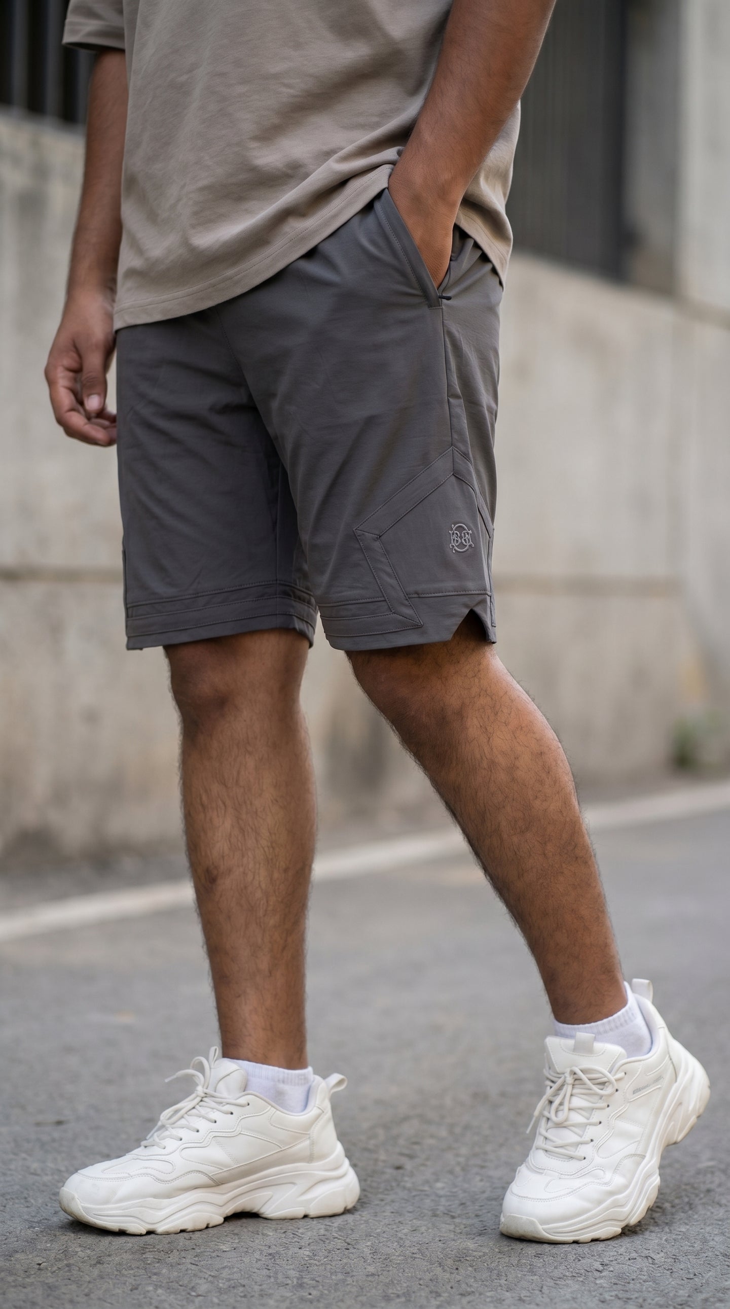 Grey cargo shorts front view with zip fly and pentagonal pocket with logo