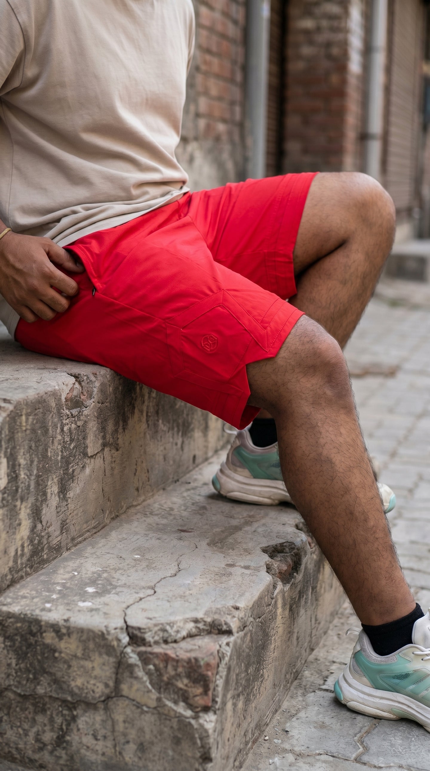 Red cargo-style shorts with pentagonal back pocket and stitched side panels