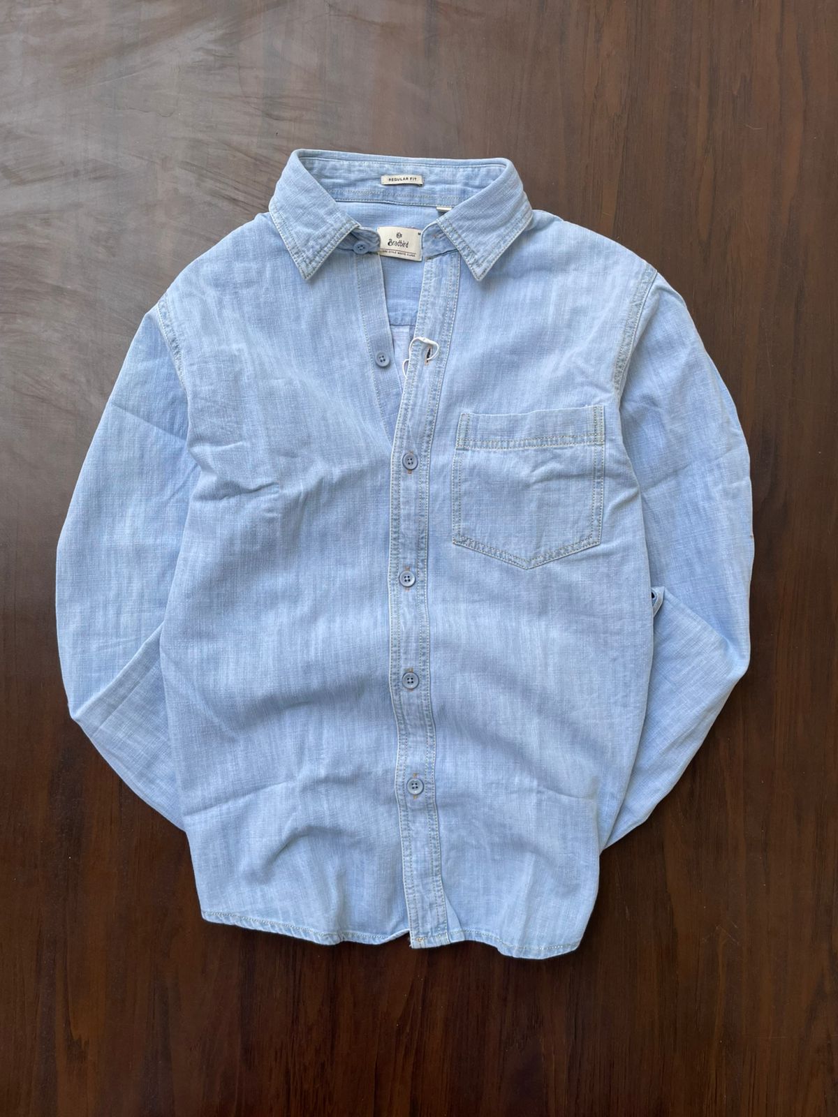 Light blue denim button-up shirt with chest pocket and regular fit label